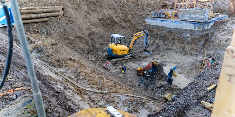 Yellow excavator at bottom of foundation ditch of construction site of apartment building at City of Zürich on an autumn day. Photo taken December 6th, 2022, Zurich, Switzerland.